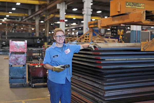 female kuhn employee standing next to steel